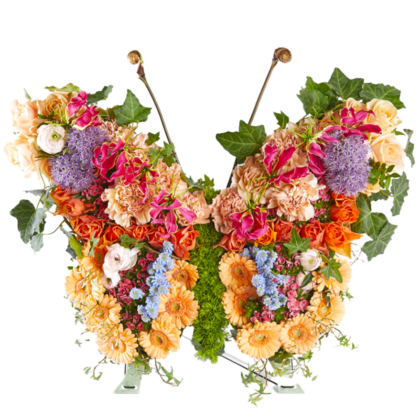 Heart-shaped floral arrangement with peach, orange, and pink blooms plus green foliage on a metal stand.