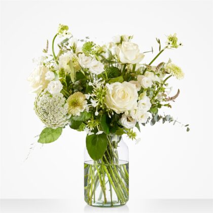 Vase with a white floral arrangement including roses, chrysanthemums, and greenery in a clear glass vase.