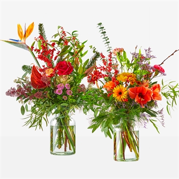 Two glass vases hold vibrant mixed flower bouquets (roses, lilies, sunflowers, and more) against a white background.