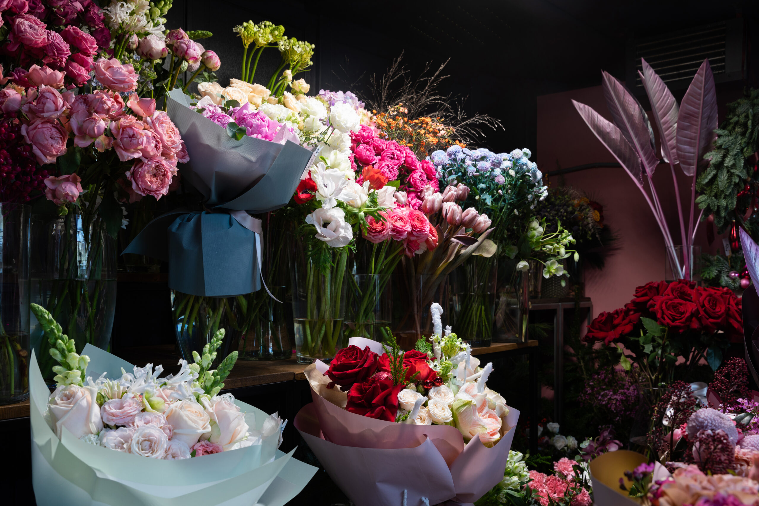 Assorted bouquets of pink, white, and red roses and other flowers in a florist shop display.